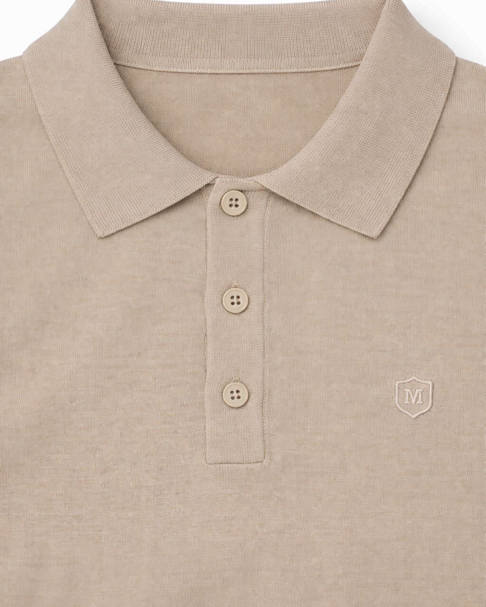 Detalle del suéter beige de punto con cuello polo y tres botones, tejido 100% algodón, ideal para moda masculina premium de alta calidad.