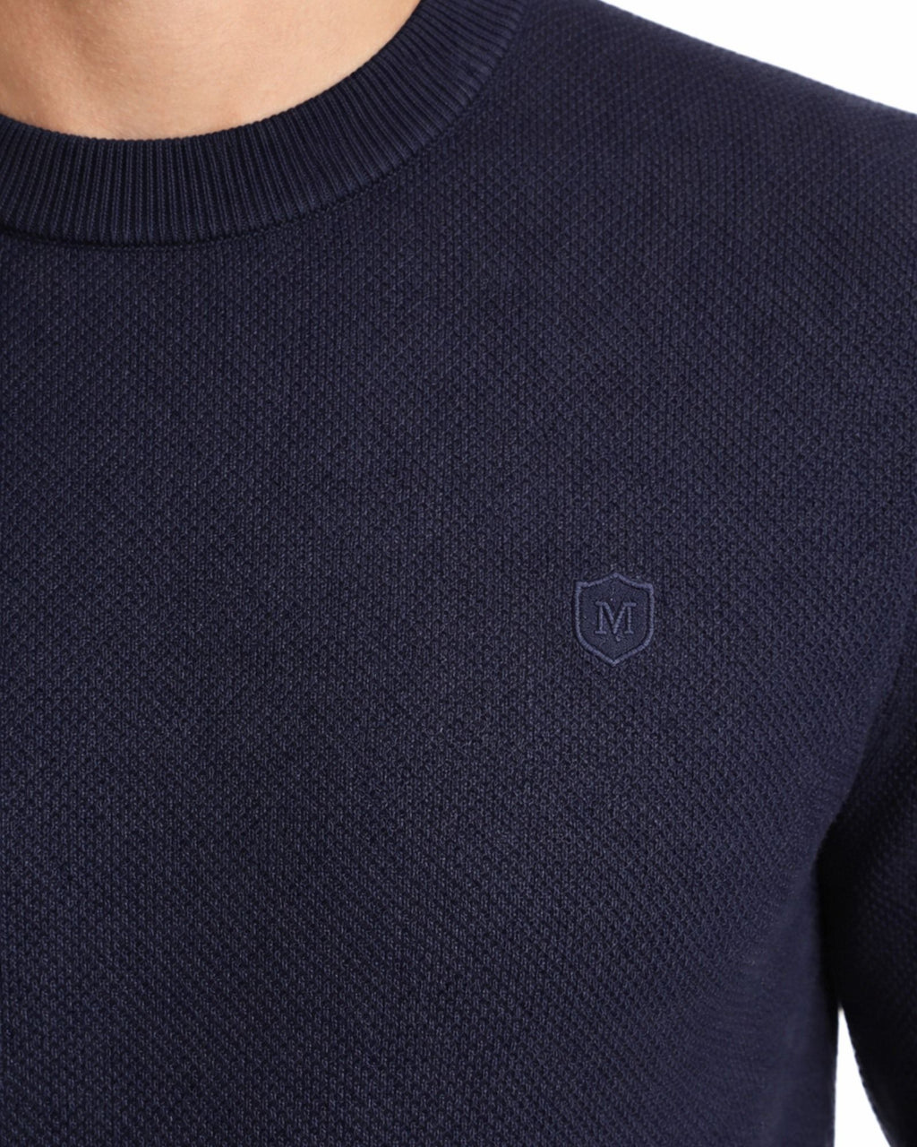 Suéter azul marino de algodón con textura estructurada y cuello redondo, detalle de logo discreto en el pecho, ideal para moda masculina premium.