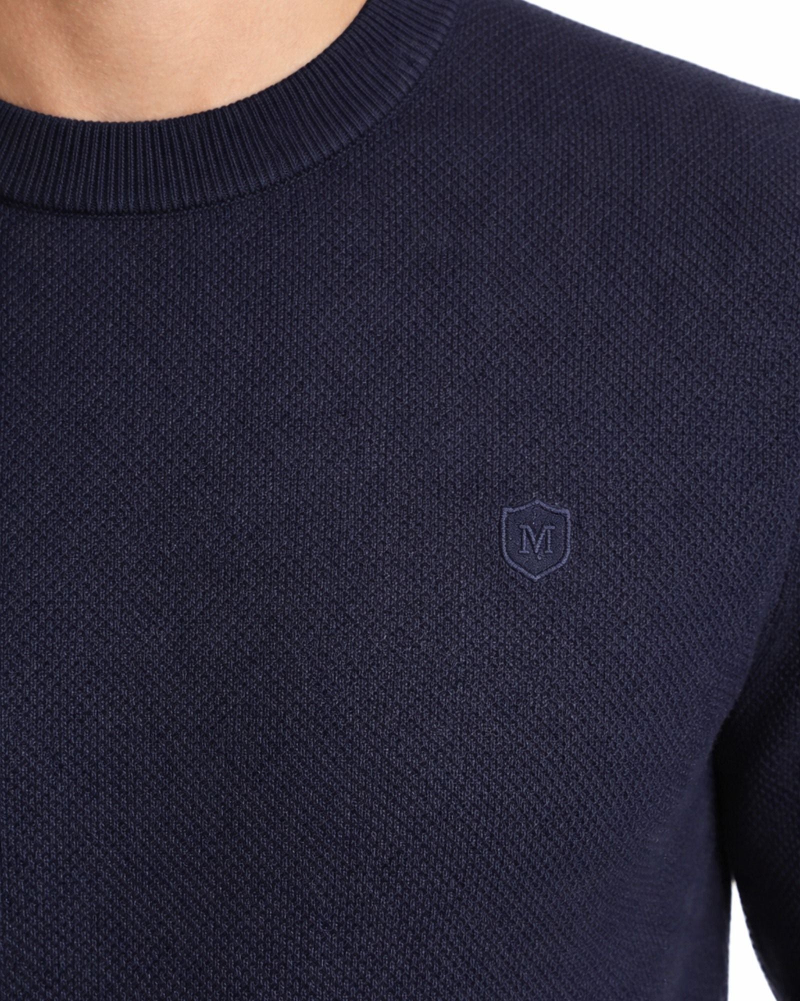 Suéter azul marino de algodón con textura estructurada y cuello redondo, detalle de logo discreto en el pecho, ideal para moda masculina premium.