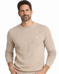 Hombre con suéter de punto beige tostado de manga larga, con cuello redondo y diseño estructurado, hecho en algodón 100% para moda masculina premium.