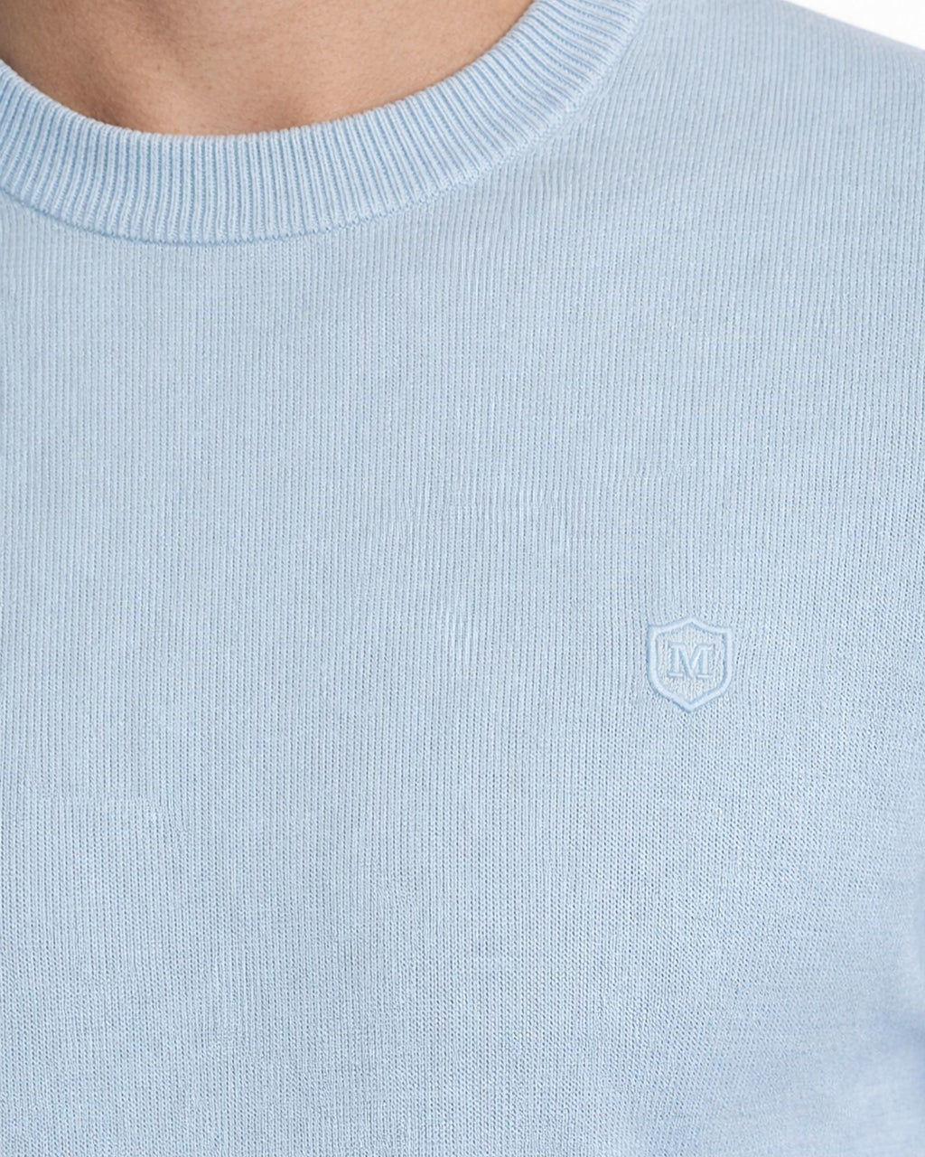 Detalle del suéter azul celeste de punto con cuello caja y tejido 100% algodón, amplio en variedad de tallas y diseño para moda masculina premium.
