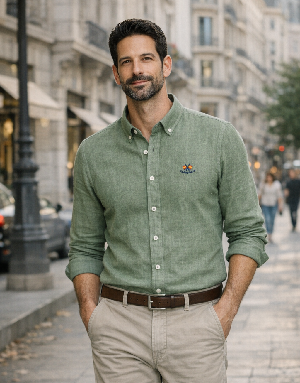 Hombre vestido con camisa de lino verde celadón de calidad premium y pantalón beige casual, posando en calle urbana con ambiente elegante y desenfadado.