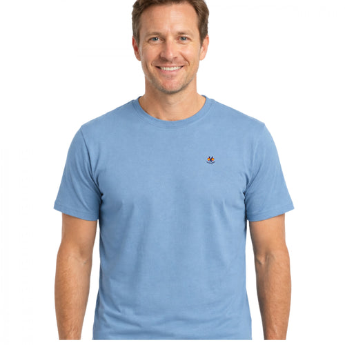 Hombre con camiseta azul celeste de algodón 100%, diseño sencillo con cuello caja y logo pequeño bordado en el pecho, ideal para moda masculina premium.