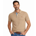 Hombre con polo beige tostado de moda masculina premium en algodón y elastano, diseño con detalle bordado y estilo elegante casual.