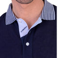 Detalle del cuello de polo azul marino para hombre con tejido de algodón y elastano, con cuello a rayas y botonería frontal, moda masculina premium.